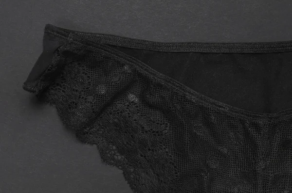 Female black lace panties on dark background top view flat lay with copy space for text. Fashion blog, Female essential erotic clothes, fashionable beautiful panties, advertising, shopping concept