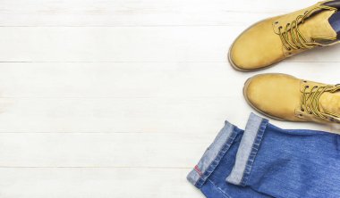 Erkek giyim, sarı iş botları doğal nubuk deri, mavi kot pantolon ve kahverengi kemer ahşap beyaz zemin üstüne düz yatıyordu kopya alanı görüntüleyin. Modaya uygun rahat ayakkabı, gençlik style, Satılık Dükkan