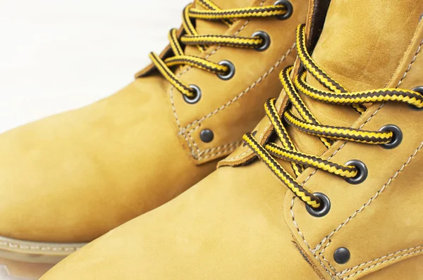 Close-up Yellow men\'s work boots from natural nubuck leather on wooden white background. Trendy casual shoes, youth style. Concept of advertising autumn winter shoes, sale, shop