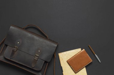 Moda kavramı. Kahverengi deri erkek çanta, günlük defter, deri pasaport kapağı ve kalemi siyah arka plan en iyi görünüm düz üzerinde kopya alanı ile yatıyordu. Aksesuarlar işadamı şık erkek iç giyim