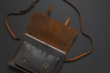 Moda kavramı. Kahverengi deri erkek çanta siyah arka plan en iyi görünüm düz üzerinde kopya alanı ile yatıyordu. İş, aksesuar işadamı, şık erkek iç giyim, iş geçmişi için evrak çantası