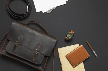 Moda kavramı. Kahverengi deri erkek çanta, kol saati, deri pasaport kapağı, kalem, siyah arka plan en iyi görünüm düz lay kopya alanı aksesuarları işadamı şık giysiler ile boş beyaz sayfalarda