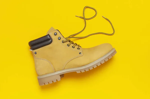 Fashionable concept. Yellow men\'s work boots from natural nubuck leather on bright yellow background top view flat lay with copy space. Trendy casual shoes, youth style Advertising sale shop