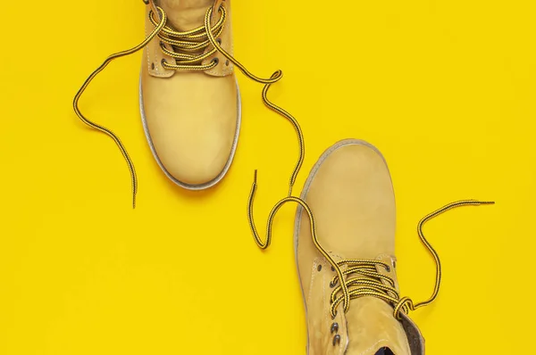 Fashionable concept. Yellow men's work boots from natural nubuck leather on bright yellow background top view flat lay with copy space. Trendy casual shoes, youth style Advertising sale shop