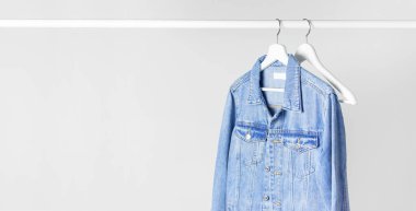 Mavi kot ceket karşı açık gri bir çubuk üzerinde beyaz ahşap askı üzerinde duvar düz yatıyordu kopya alanı. Denim, moda ceket, kadın ya da erkek trend giyim, moda arka plan. Mağaza konsepti, Satılık