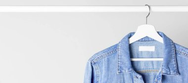 Mavi kot ceket karşı açık gri bir çubuk üzerinde beyaz ahşap askı üzerinde duvar düz yatıyordu kopya alanı. Denim, moda ceket, kadın ya da erkek trend giyim, moda arka plan. Mağaza konsepti, Satılık