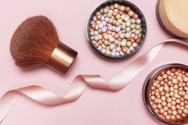 Top inci allık, yüz pudrası, makyaj fırça ve pembe kurdele pastel pembe arka plan en iyi görünümüyle düz koymak kopya alanı. Çeşitli kozmetik ürünleri, Makyaj Aksesuarları