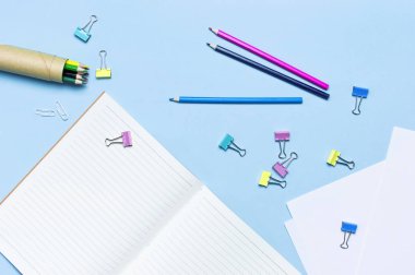 Ahşap renkli kalemler, temiz öğrenci yarıyıl Not defteri satırında, ataç mavi arka plan üstüne düz yatıyordu kopya alanı görüntüleyin. Çizim nesneleri için yaratıcılık için kurşun kalem. Geri okul kavramı