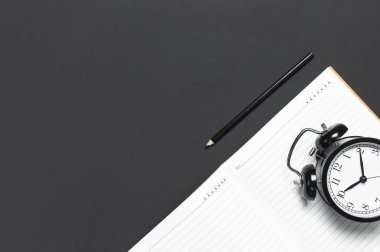 Düz siyah çalar saat, temiz açık defter günlüğü yatıyordu, gri koyu arka plan üstten görünüm Kopyala yer üstünde kalem. İş, okul sırası, Office Resepsiyon minimalist arka plan kavramı zaman blog için