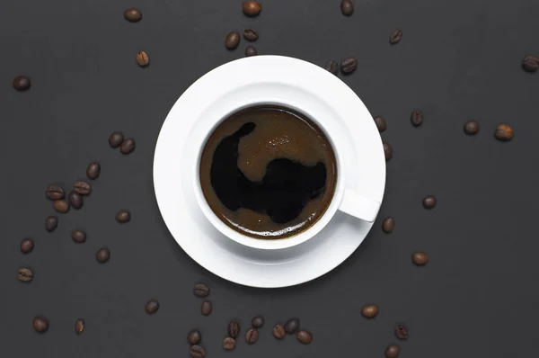 Flat lay cup of black coffee and coffee beans on gray dark background top view copy space. Minimalistic food concept, morning breakfast, time to work, hot drink coffee background