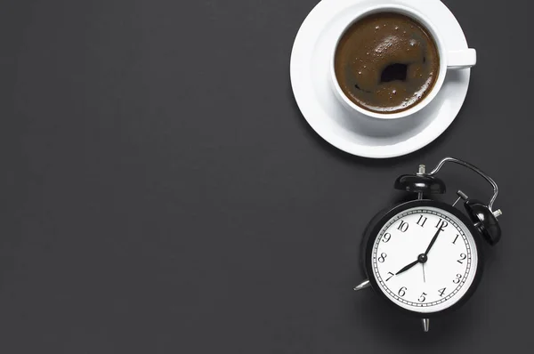 フラット ブラック コーヒーのカップを置く 黒灰色の暗い背景平面図コピー スペースの目覚まし時計 最小限の食品のコンセプト 朝の朝食 仕事に時間ホット コーヒーを飲む背景 — ストック写真