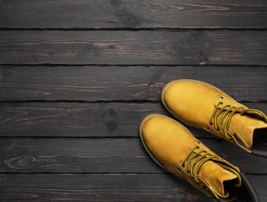 Sarı mens doğal nubuk deri çizmeler koyu ahşap arka plan en iyi görünüm düz lay kopya alanı ile çalışmak. Modaya uygun rahat ayakkabı, gençlik tarzı. Sonbahar Kış ayakkabı satış dükkanı reklam kavramı