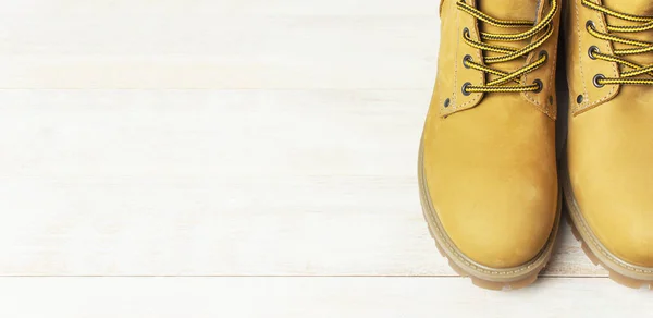 Close-up Yellow men's work boots from natural nubuck leather on wooden white background. Trendy casual shoes, youth style. Concept of advertising autumn winter shoes, sale, shop