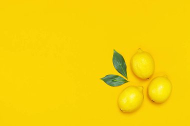 Olgun sulu limon ve parlak sarı zemin üzerine yeşil yaprakları. Limon meyve, narenciye en az kavramı, vitamin C. yaratıcı yaz yiyecek minimalist arka plan. Düz yatıyordu, en iyi görünüm, kopya alanı
