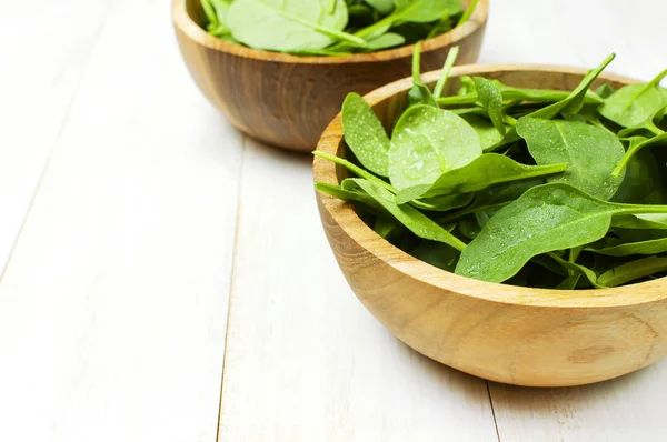 Fresh green spinach leaves on wooden bowl on white wooden rustic background Selective focus copy space. Baby young spinach leaves, Ingredient for salad, healthy food, diet. Nutrition concept