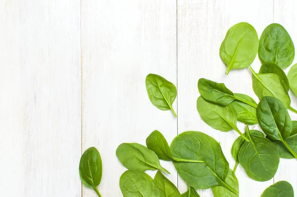 Fresh green spinach leaves on white wooden rustic background top view copy space. Baby young spinach leaves, Ingredient for salad, healthy food, diet. Nutrition concept