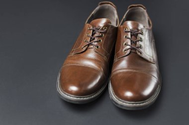 Klasik kahverengi deri erkek ayakkabı gri siyah arka plan en iyi görünüm düz kopya alanı ile yatıyordu. Moda erkek kavramı, hakiki deri ayakkabılar. Saklamak reklam, satış, dükkanı