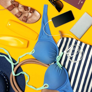 Kadın yaz Giyim Aksesuarları Sarı zemin üzerine. Seyahat tatil deniz kavramı. Şapka takım elbise kot şort deri sandalet güneş gözlüğü güneş deniz çanta pasaport telefon yüzme. Düz yatıyordu Üstten Görünüm