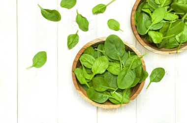 Taze yeşil ıspanak üzerinde beyaz ahşap rustik arka plan üstten görünüm kopya alanı ahşap kase yaprak. Bebek Genç ıspanak yaprakları, salata, sağlıklı gıda, diyet için madde. Beslenme kavramı.