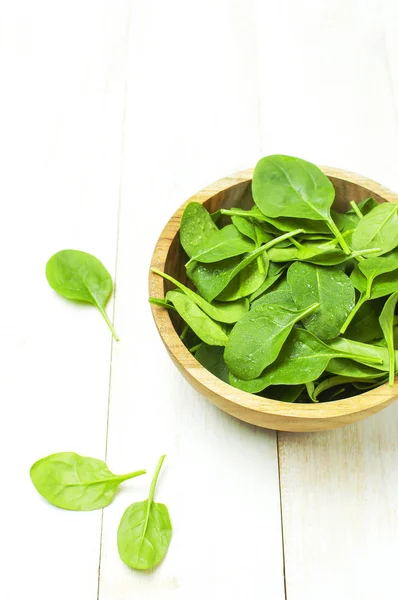 Fresh green spinach leaves on wooden bowl on white wooden rustic background Selective focus copy space. Baby young spinach leaves, Ingredient for salad, healthy food, diet. Nutrition concept.