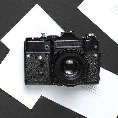 Eski retro vintage fotoğraf makinesi, en iyi görünüm düz siyah arka plan üzerinde beyaz boş fotoğraf kartları kopya alanı ile yatıyordu. Fotoğrafçı, eski fotoğrafik donanımlar, minimalist tarzı seçici odak için kavram
