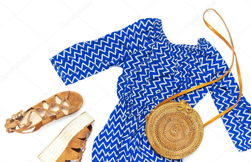 Stylish trendy feminine summer clothing blue dress jumpsuit, sandals round rattan bag sprig eucalyptus on white background Trendy hipster look Female fashion background blog concept Flat lay top view