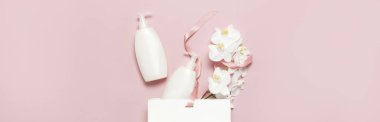 Düz üstten görünüm beyaz kozmetik şişe kapları hediye çanta beyaz Phalaenopsis orkide çiçek pembe bir arka plan üzerinde yatıyordu. Mock-up doğal organik güzellik ürün kavramı minimalizm tarzı marka kozmetik Spa