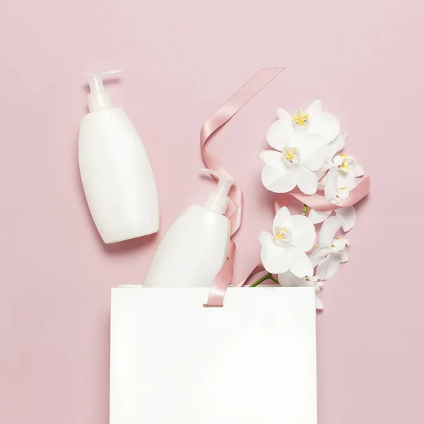 Плоский вид сверху Белый косметический контейнер для бутылок подарочный пакет Белый цветок орхидеи Фаленопсис на розовом фоне. Косметика SPA брендинг макет-ап Природные органические красоты концепция продукта Минимализм стиль — стоковое фото