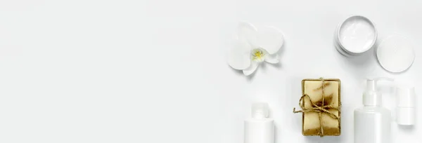 Witte cosmetische fles containers, natuurlijke zeep, orchideebloem op witte achtergrond bovenaanzicht plat lag. Cosmetica Spa branding mock-up. Biologische natuurschoon productconcept. Minimalisme cosmetica stijl — Stockfoto