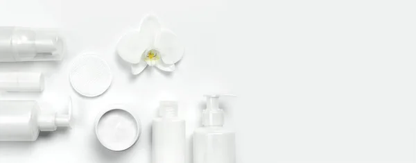 Witte cosmetische fles containers en orchideebloem witte achtergrond bovenop bekijken plat lag. Cosmetica Spa branding mock-up, natuurlijke organische schoonheid productconcept, minimalisme cosmetica stijl — Stockfoto