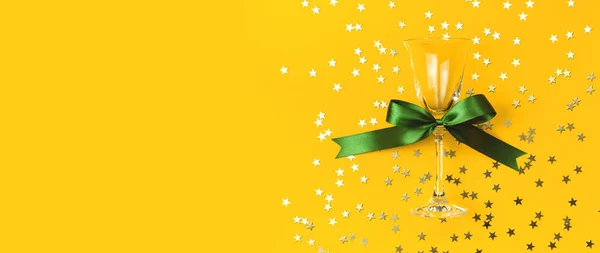 Copos de champanhe com fita verde, confetis dourados em forma de estrelas sobre fundo amarelo Flat lay Vista superior. Composição criativa, conceito de fogos de artifício festa de aniversário Natal ano novo — Fotografia de Stock