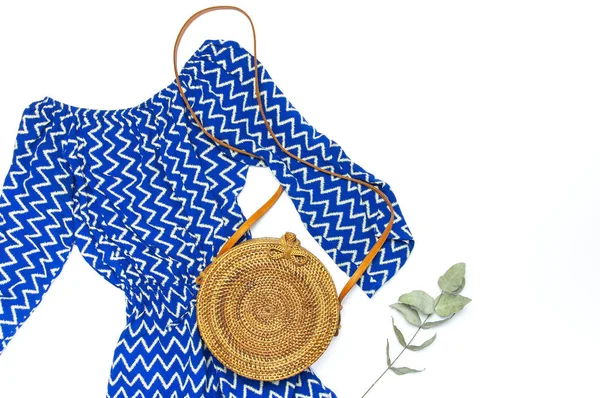 Стильная модная женская летняя одежда голубой комбинезон платье, круглый мешок ротанга веточка эвкалипт на белом фоне — стоковое фото