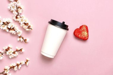 Kahve veya çay kağıt fincan, kalp şeklinde acıbadem kurabiyesi kek, pembe arka plan üst görünüm düz yatıyordu beyaz çiçekler bahar dalları. Kahve kupasını al, mockup. Kahve aşk kavramı, tasarım düzeni