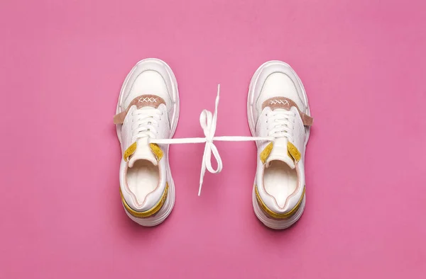Witte vrouwelijke sneakers op heldere roze achtergrond. Fashion blog of magazine concept. Damesschoenen, trendy Sneakers, mode, stijl, lifestyle. Platte lay bovenaanzicht kopie ruimte minimale achtergrond. — Stockfoto