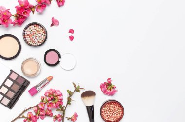Farklı makyaj kozmetik. Ball allık rouge yüz pudra ruj kapatıcı şişe parfüm göz farı makyaj fırça bahar pembe çiçekler açık arka plan üst görünümü düz yatıyordu. Güzellik moda arka plan
