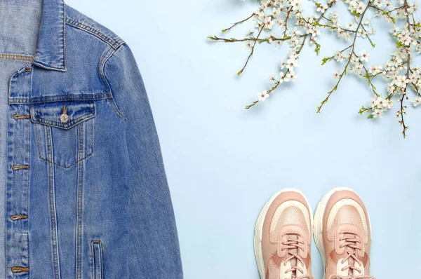 Jaqueta de ganga azul, tênis rosa na moda, flores de primavera no fundo azul vista superior plana leigos espaço de cópia. Denim, jaqueta elegante, roupas de tendência feminina ou masculina, fundo de beleza de moda primavera . — Fotografia de Stock