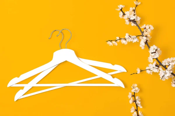 Creatieve mode Beauty achtergrond. Witte houten hangers en lente bloeiende tak op gele achtergrond. Spring SALE concept Discount Store winkelen lege hanger promo design platte lay Top View — Stockfoto