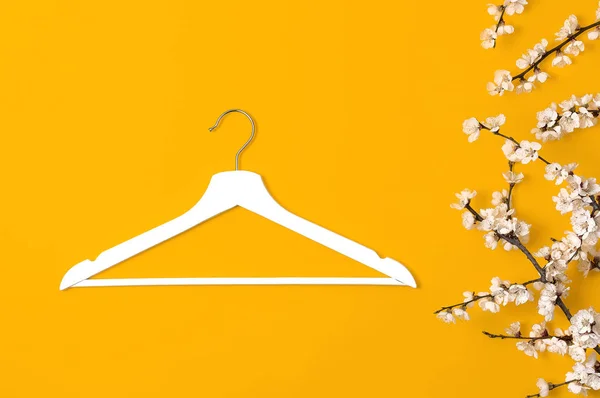 Fondo de belleza de moda creativa. Percha de madera blanca y rama floreciente de primavera sobre fondo amarillo. concepto de venta de primavera tienda de descuento compras diseño promocional percha vacía. Vista superior plana —  Fotos de Stock