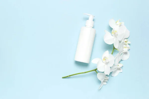 Плоский вид сверху Белый косметический контейнер для бутылок Белый цветок орхидеи Фаленопсис на голубом фоне. Косметика SPA брендинг макет-ап Природные органические красоты концепция продукта Минимализм стиль — стоковое фото