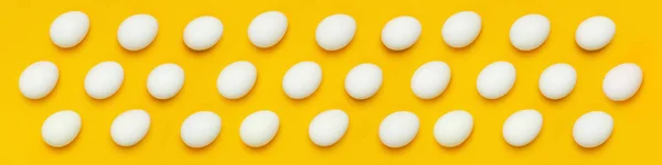 Patrón de huevos de pollo blanco sobre fondo amarillo vista superior plana poner espacio de copia. Alimentos creativos fondo minimalista, Pascua. Concepto natural de alimentación saludable y agricultura ecológica . — Foto de Stock