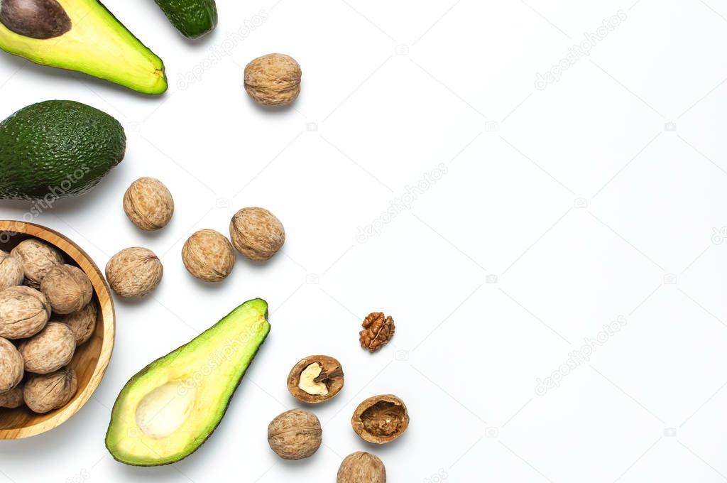 Ripe fresh avocado and walnuts in wooden bowl on white background top view Flat lay copy space. Fruits Healthy food concept, diet, healthy lifestyle.