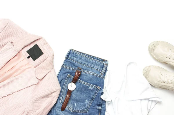 Стильний жіночий весняний одяг біла сорочка, сині джинси, рожева куртка кордуроя, бежеві шпигуни, годинники на білому тлі. Модний вигляд хіпстера. Концепція жіночого фонового блогу Плоский вигляд зверху — стокове фото