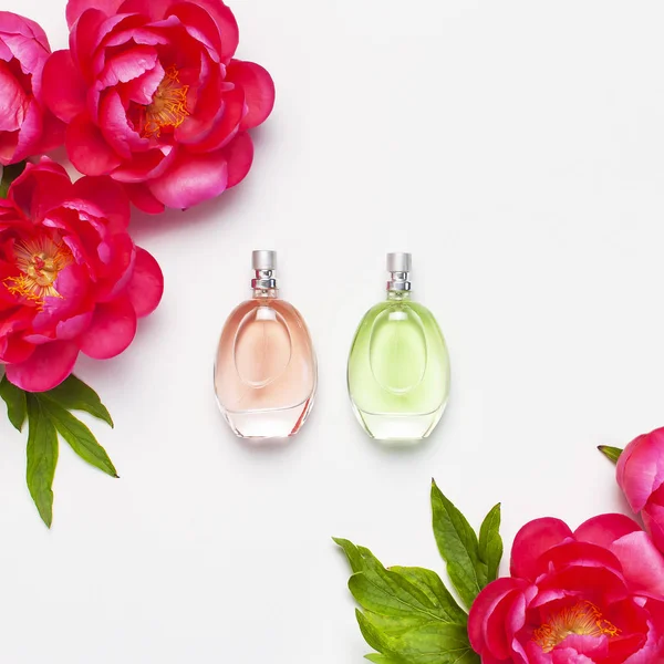 Perfume bottles and pink flowers peonies on light gray background top view Flat lay copy space. Perfumery, cosmetics, female accessories, fragrance collection. Delicate Perfume Bottle.