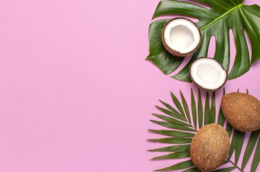 Tropikal yaprakları ve pembe arka plan üzerinde taze hindistan cevizi. Düz döşeme, üst görünüm, kopyalama alanı. Yaz geçmişi, doğa. Sağlıklı yemek pişirme. Yaratıcı sağlıklı gıda kavramı, hindistan cevizi yarısı