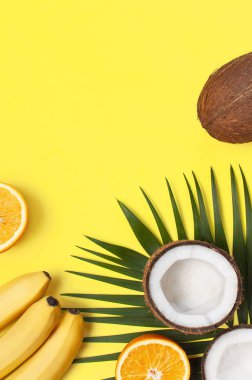 Yaz tropikal kompozisyon. Palmiye ağaçları ve monstera, hindistan cevizi, portakal, parlak sarı arka plan üzerinde muz yeşil tropikal yaprakları. Düz döşeme, üst görünüm, kopyalama alanı. Yaratıcı arka plan gıda, meyve
