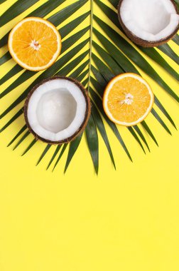 Yaz tropikal kompozisyon. Palmiye ağaçları ve monstera, hindistan cevizi, parlak sarı arka plan turuncu yeşil tropikal yaprakları. Düz döşeme, üst görünüm, kopyalama alanı. Yaratıcı arka plan gıda, meyve