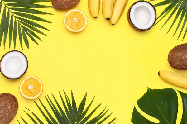 Summer tropical composition. Frame of Green tropical leaves of palm trees and monstera, coconut, orange, bananas on bright yellow background. Flat lay, top view, copy space. Fruit Background
