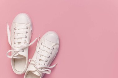 Pembe arka planda beyaz kadın moda ayakkabıları. Düz konum, üst görünüm, kopyalama alanı. Kadın ayakkabıları. Şık beyaz ayakkabılar. Moda blogu ya da dergi konsepti. Minimalist ayakkabı arkaplanı, spor ayakkabıları