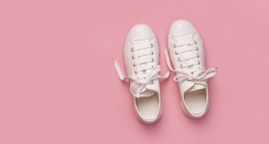 Pembe arka planda beyaz kadın moda ayakkabıları. Düz konum, üst görünüm, kopyalama alanı. Kadın ayakkabıları. Şık beyaz ayakkabılar. Moda blogu ya da dergi konsepti. Minimalist ayakkabı arkaplanı, spor ayakkabıları