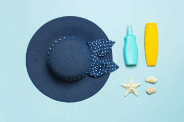 Yaz konsepti, deniz geçmişi. Deniz kabukları, denizyıldızı, dişi hasır şapka, pastel mavi arka plan üzerinde güneş kremi vücut kremi sprey. Üst görünüm, düz döşeme, kopyalama alanı. Deniz yaz tatili Mockup. Seyahat